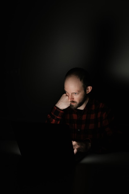 Фото Парень устало смотрит на ноутбук в темноте
