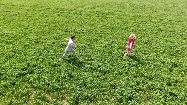 写真 男は小麦畑で女の子を追いかけている 男と女は畑を歩いている 愛の関係は草の上で走っている