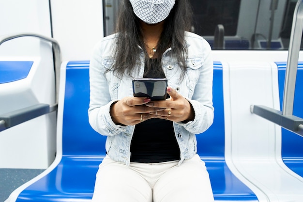 スマートフォンを使って地下鉄の車に座っている認識できない黒人女性の手