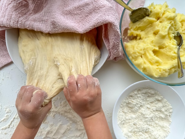 Фото Руки ребенка перемешивают тесто для приготовления пирогов на белом столе