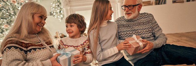 写真 子供たちに贈り物をする幸せな祖父母