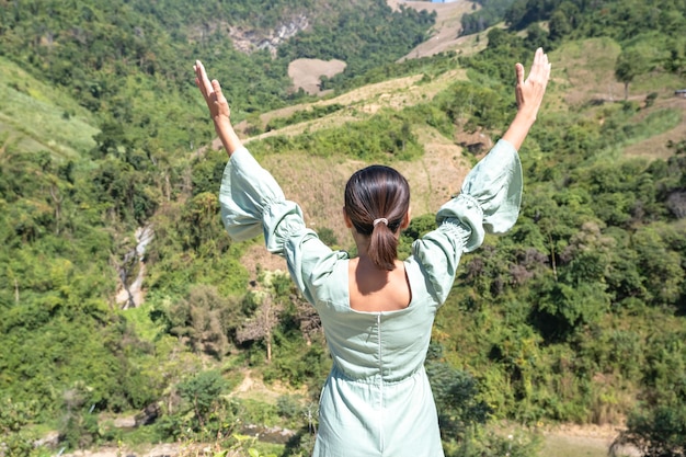 写真 山や木々を見ながら腕を上げる女性たちの後ろ姿。