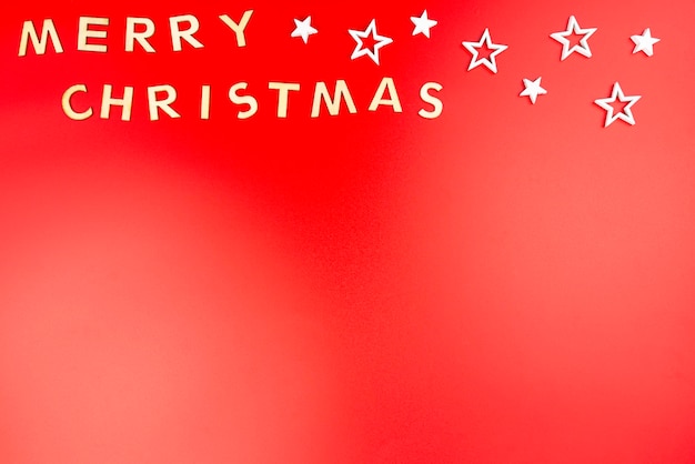 사진 나무 글자로 만든 '메리 크리스마스'라는 글자는 빨간색에 고립되어 위에서 평평하게 놓여 있습니다.