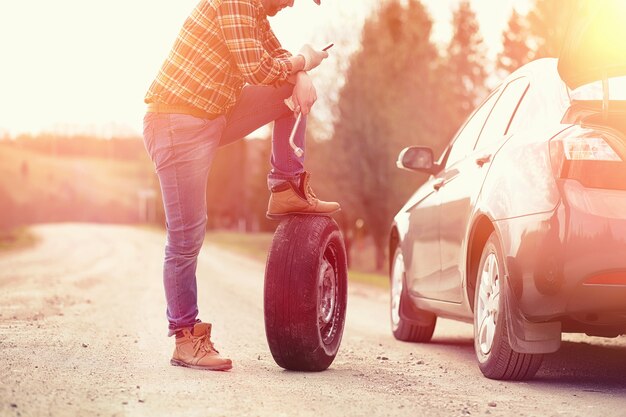 写真 男は自然の中で車のそばの道路に座っています