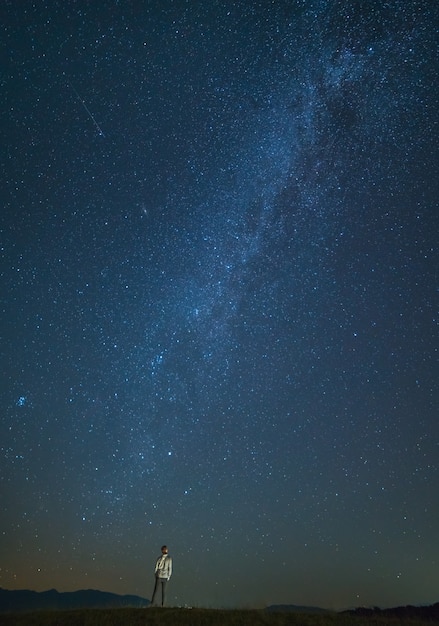 男は星空の背景に立っています。夜の時間