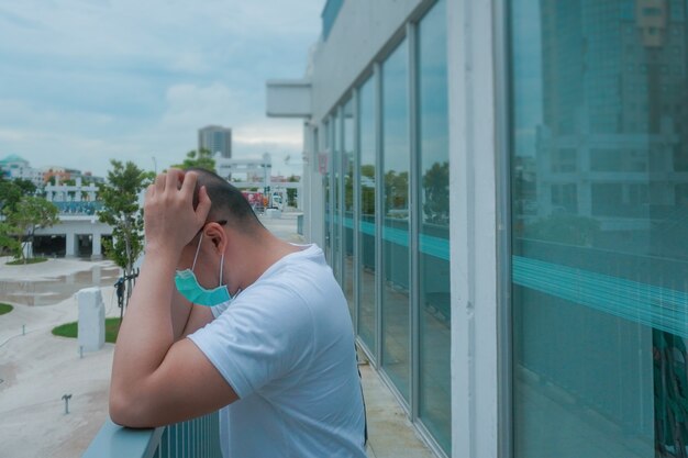 사진 마스크를 쓴 남자는 옥상 건강 문제 개념에서 두통 편두통으로 몸이 좋지 않다고 느낀다