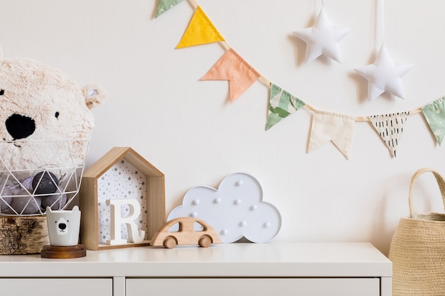 Фото Современная скандинавская комната для новорожденных с копией пространства, деревянной машинкой, плюшевыми игрушками и облаками.