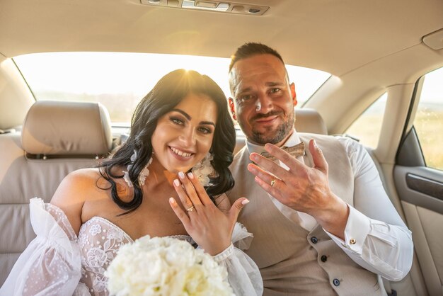 사진 신혼 부부는 차에서 미소 짓고 반지를 보여주고 있습니다.