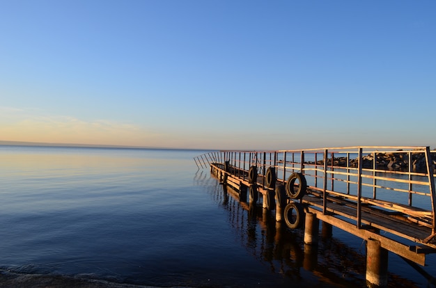 写真 日没で太陽に照らされ、水と澄んだ空に囲まれたヴォルガ川の古い桟橋