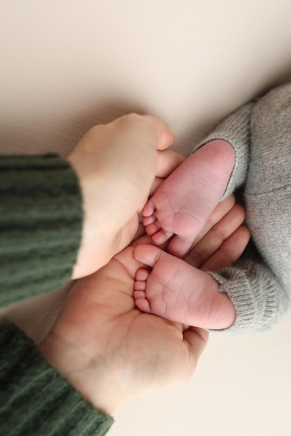 Фото Пальмы отца, мать держат ногу новорожденного ребенка, ноги новорожденого на ладонях родителей, макрофото в студии пальцев ног, каблуков и ног ребенка на белом фоне.