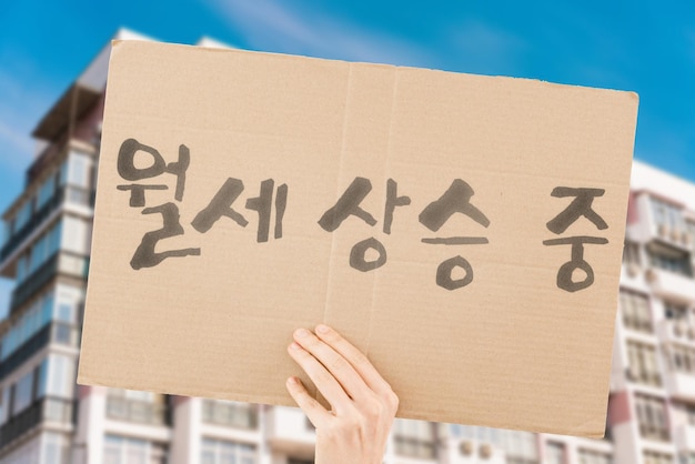 사진 임대료가 오르고 있다는 문구는 남성의 손에 있는 현수막에 있습니다 아파트 부동산 시장 비용 돈 성장 비싼 플랫 하우스