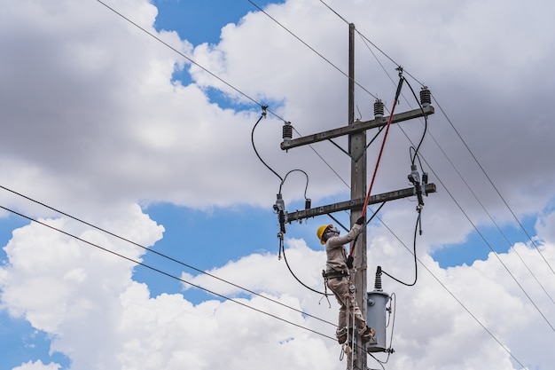 写真 電力線技師は、クランプスティック（絶縁工具）を使用して、高電圧の高圧電力線の変圧器を閉じます。