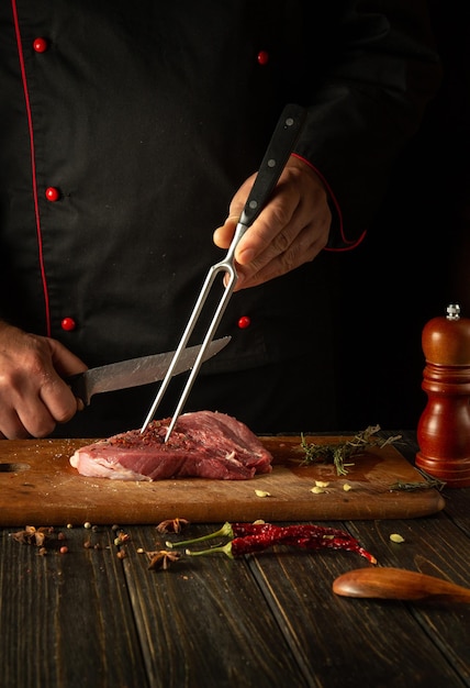 写真 料理人の手で牛肉のステーキを準備するプロセス レストランのキッチンテーブルで美味しい肉のランチを準備するためのスパイスとローズマリー