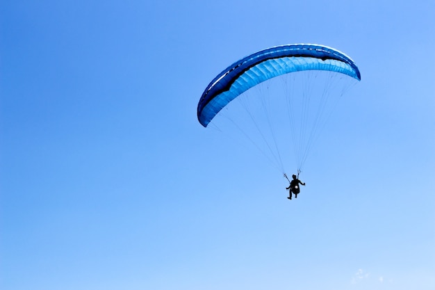 青い空のパラグライダーで飛んでいるスポーツマン