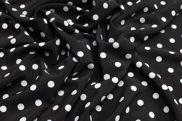Фото Текстура шелковой ткани с белым горошком на черном.