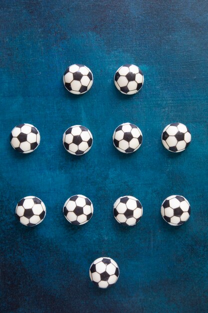 Фото Традиционное расположение игроков на футбольном поле - четыре-четыре-два. игроки отмечены шоколадными тортами в виде мячей для европейского футбола черным по белому.