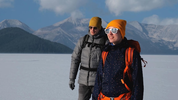 写真 雪山の背景に立っているバックパックを持つ 2 人の旅行者