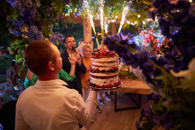 写真 ウェイターは花火でバースデーケーキを手に持っています