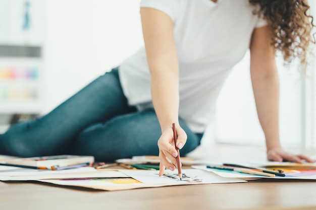 写真 テーブルに座って紙に描く女性