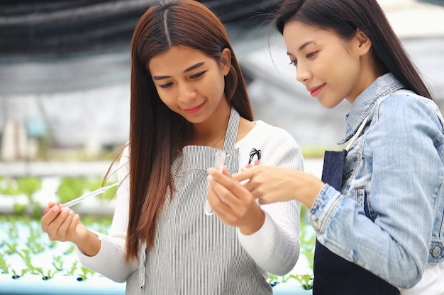 写真 養液栽培の野菜畑と彼女のコンサルタントを所有している女性。彼らは野菜畑で水の状態をテストしています。