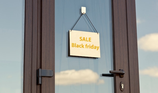 Фото Деревянный знак с текстом распродажа черная пятница висит на двери в магазине
