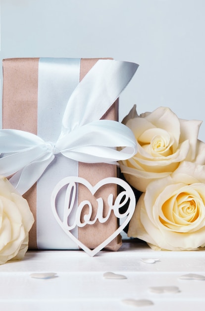 Фото Слово любовь белыми буквами на подарочных коробках с белыми лентами и желтыми розами