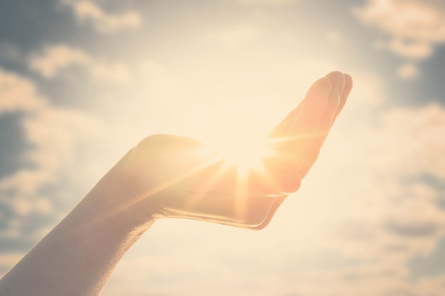 写真 黄色い太陽は女性の手のひらにあります