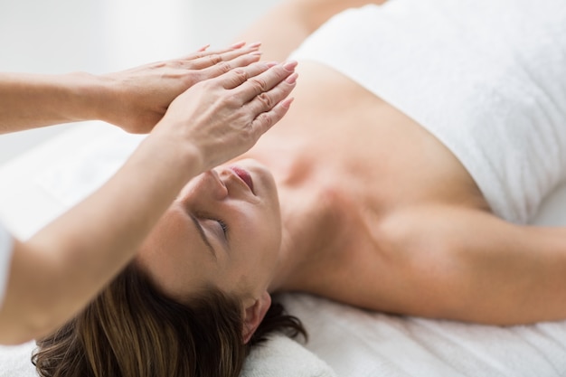 Thearapist performing reiki on woman