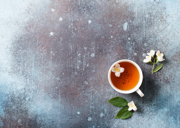 Foto thee jasmijn achtergrond met theepot, bladeren en bloemen op donkere textuur, bovenaanzicht, kopie ruimte