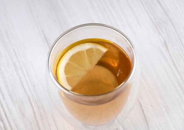 Thee met citroen in een glazen beker op een houten tafel, vrije ruimte. Nuttig drankje. Verwarmend drankje