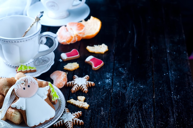 Theekopje met thee en koekjes engel, mandarijn een zwarte tafel