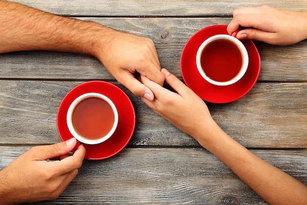 Theekopjes en hand in hand aan de houten tafel