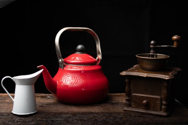 Theepot koffiemolen en melkkannetje op een donkere houten tafel