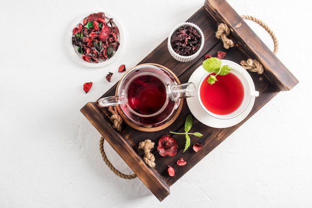 Theepot met geurige theeblaadjes, rozenhibiscus en munt op een houten dienblad bovenaanzicht natuurlijk antibioticum en antisepticum