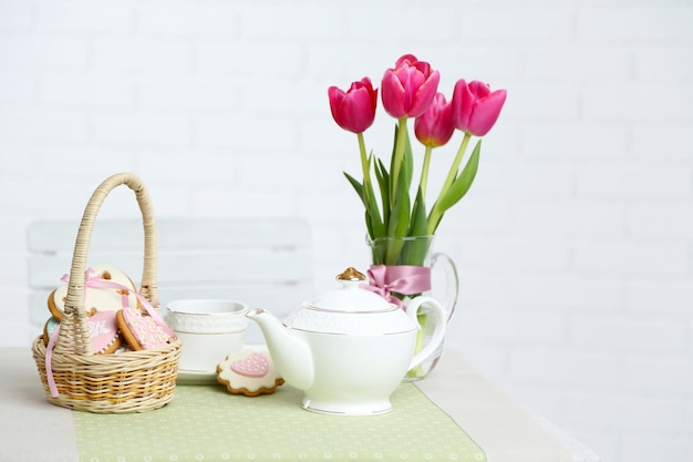 Theeservies met bloemen op tafel op lichte achtergrond