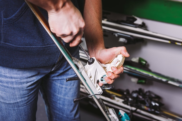 Thema tinctuur en reparatie ski-uitrusting ski. close-up van de hand van een blanke man gebruikt een handschroevendraaier om de bindingen voor skischoenen in de werkplaats te tweaken, draaien.