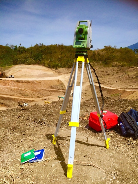 Photo theodolite with tripod on land against sky
