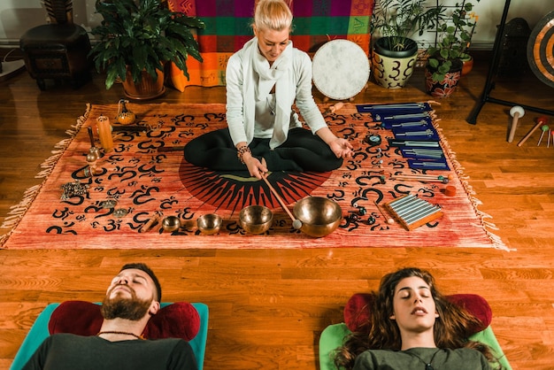 Foto therapeut speelt rin gong door een paar tijdens het uitvoeren van muziektherapie in de spa
