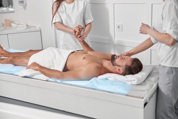 Therapeuten in uniform masseren de patiënt van middelbare leeftijd in een moderne salon