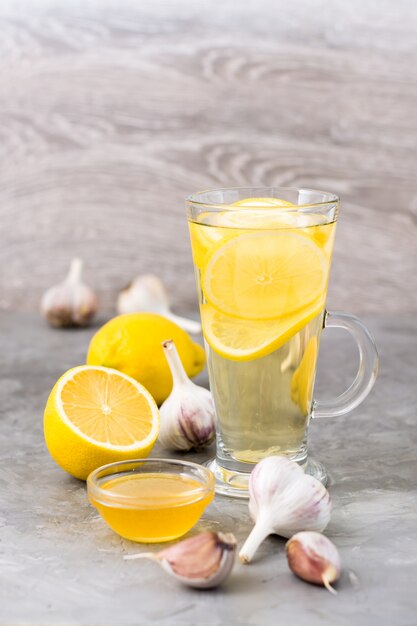 Therapeutic drink of lemon, honey and garlic in a glass on the table. Alternative medicine