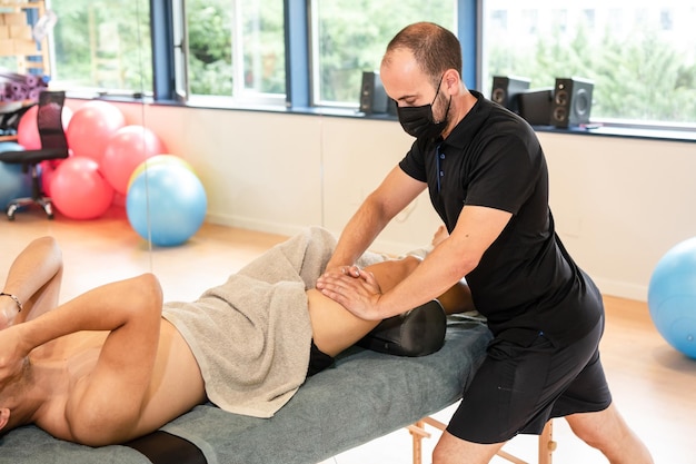 Therapeutic thigh massage and sports recovery osteopathy Sportsman receiving a massage by a physiotherapist on a stretcher