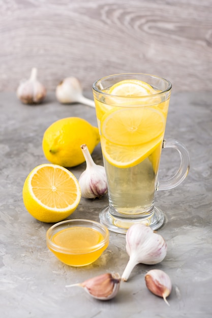 Therapeutische drank van citroen, honing en knoflook in een glas op tafel.