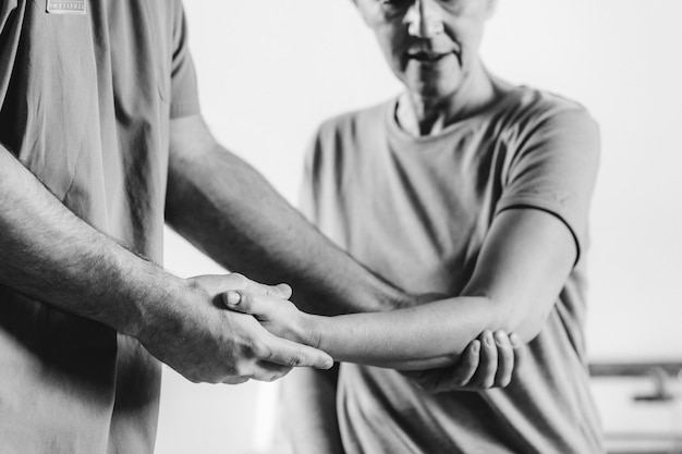 Therapist Checking Senior Woman's Arm