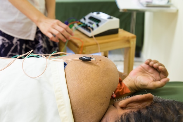 Photo therapist giving acupuncture treatment to an old man in hospital