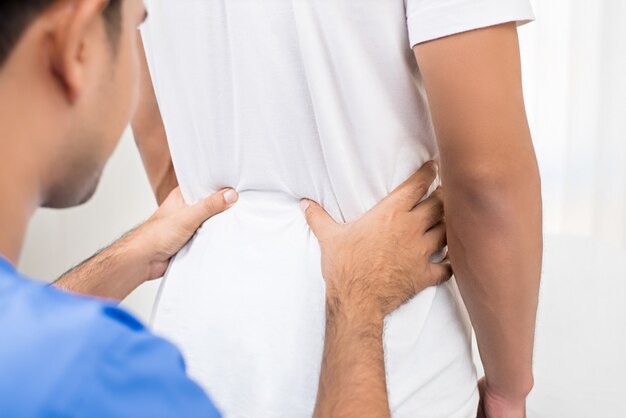 Therapist giving massage to lower back pain patient in clinic 