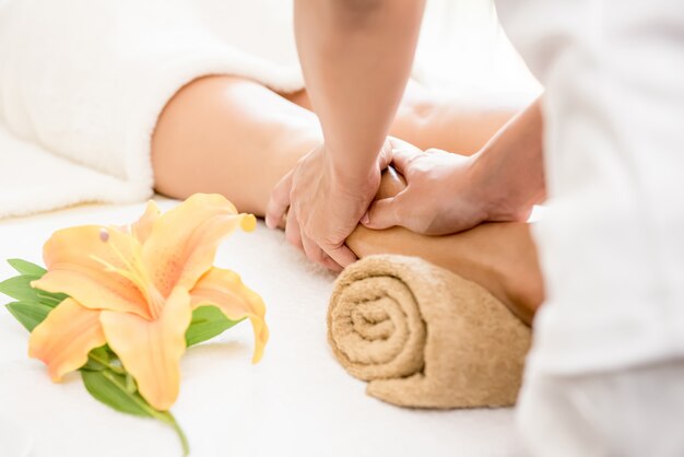 Therapist giving reflexology relaxing Thai leg spa massage 