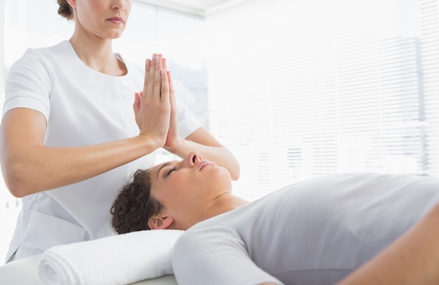 Therapist giving Reiki treatment to woman