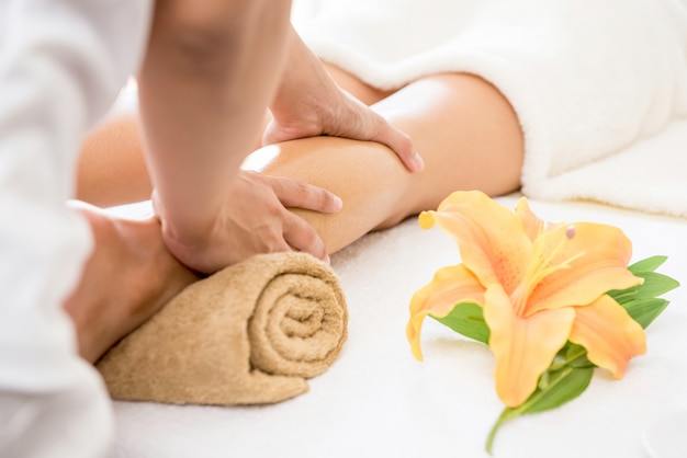 Therapist giving relaxing Thai oil leg massage treatment to a woman in spa