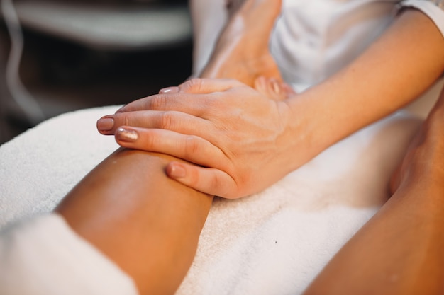 Foto terapista sta massaggiando le gambe del cliente durante una procedura di cura della pelle