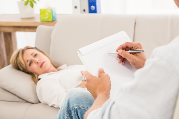 Therapist listening to female patient and taking notes